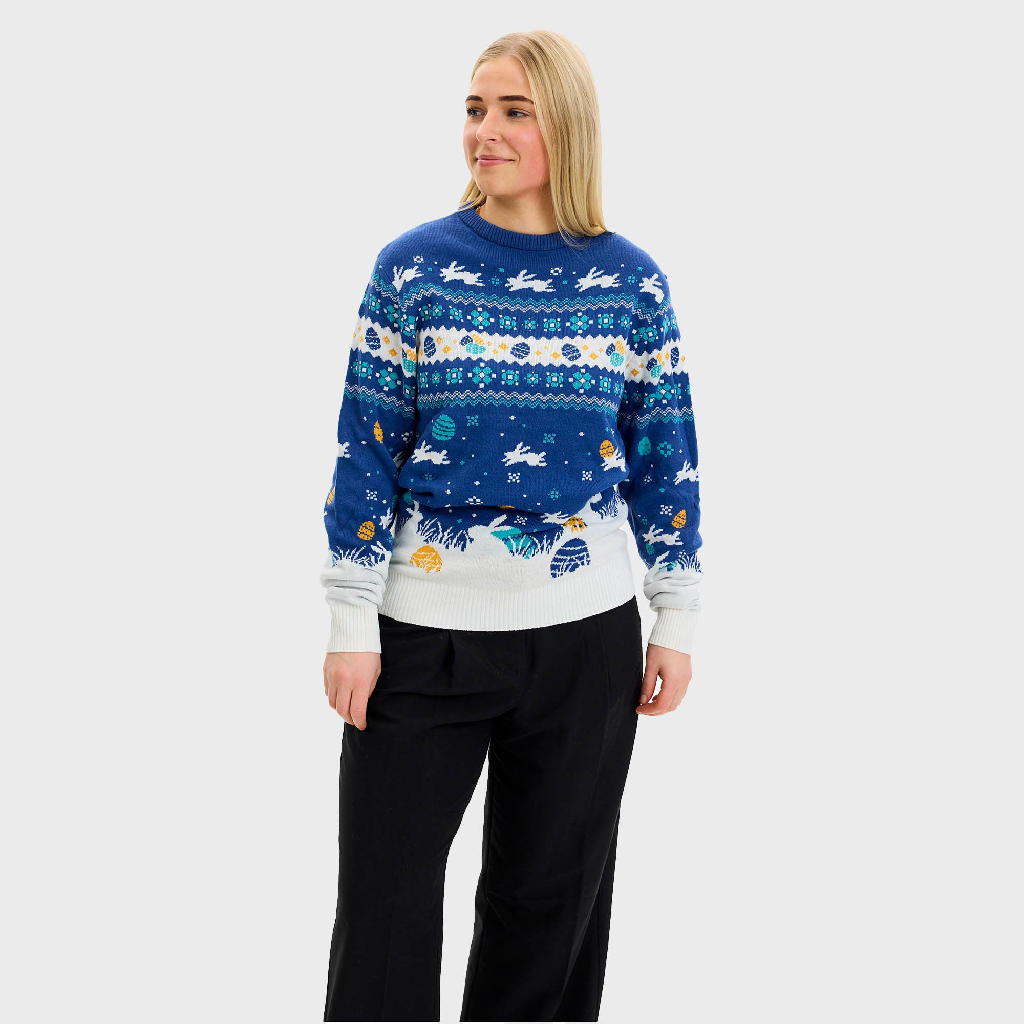 En mann og en kvinne som ser på en påskehare og har på seg en blå påskegenser med kaniner på.