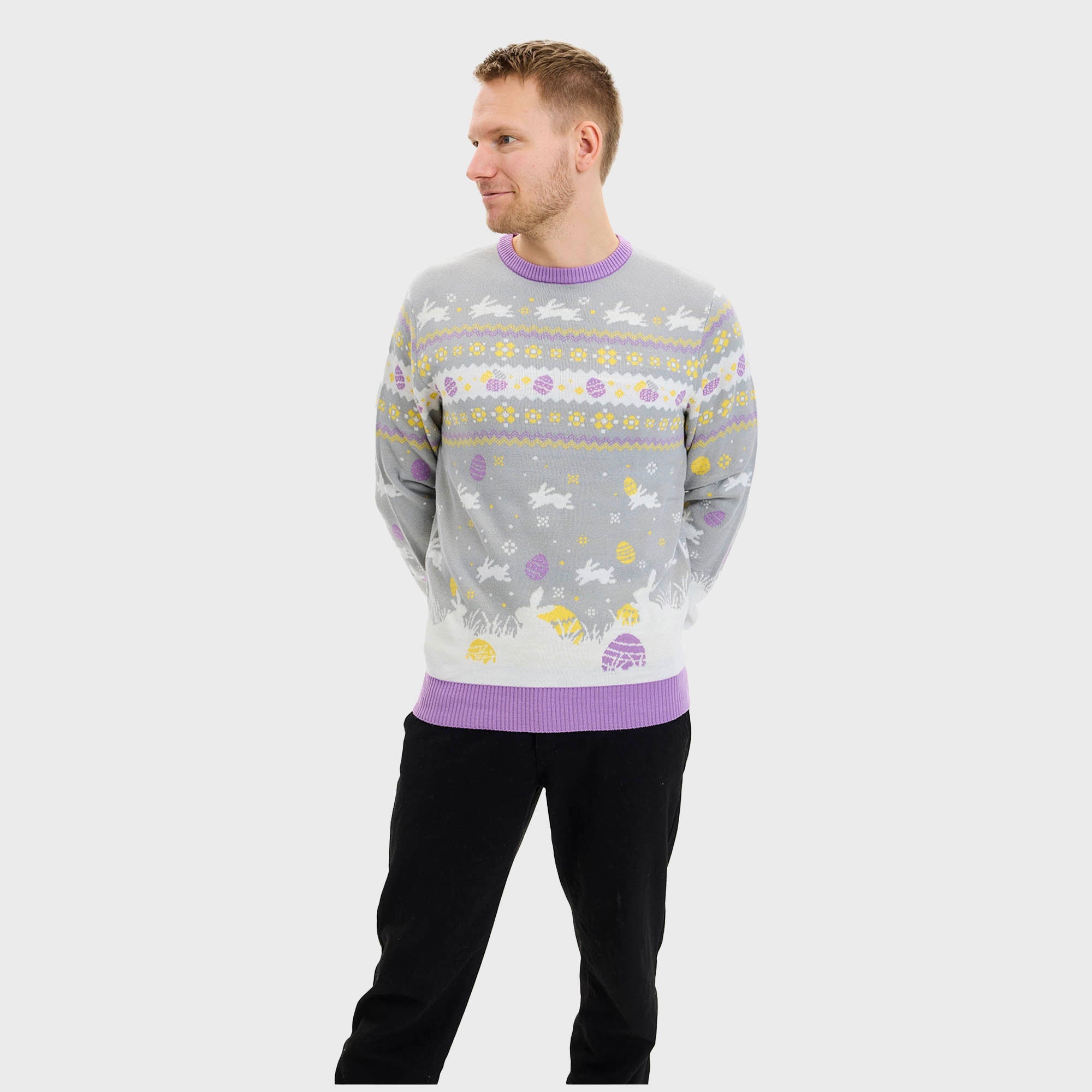 En smilende mann som ser ned på seg selv iført en grå påskegenser med kaniner på.