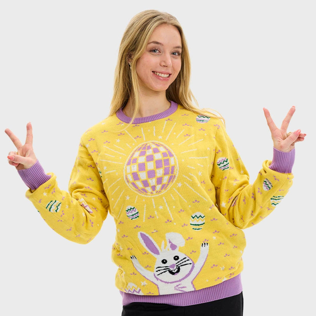 En kvinne i gul påskegenser med diskokule og kanin.