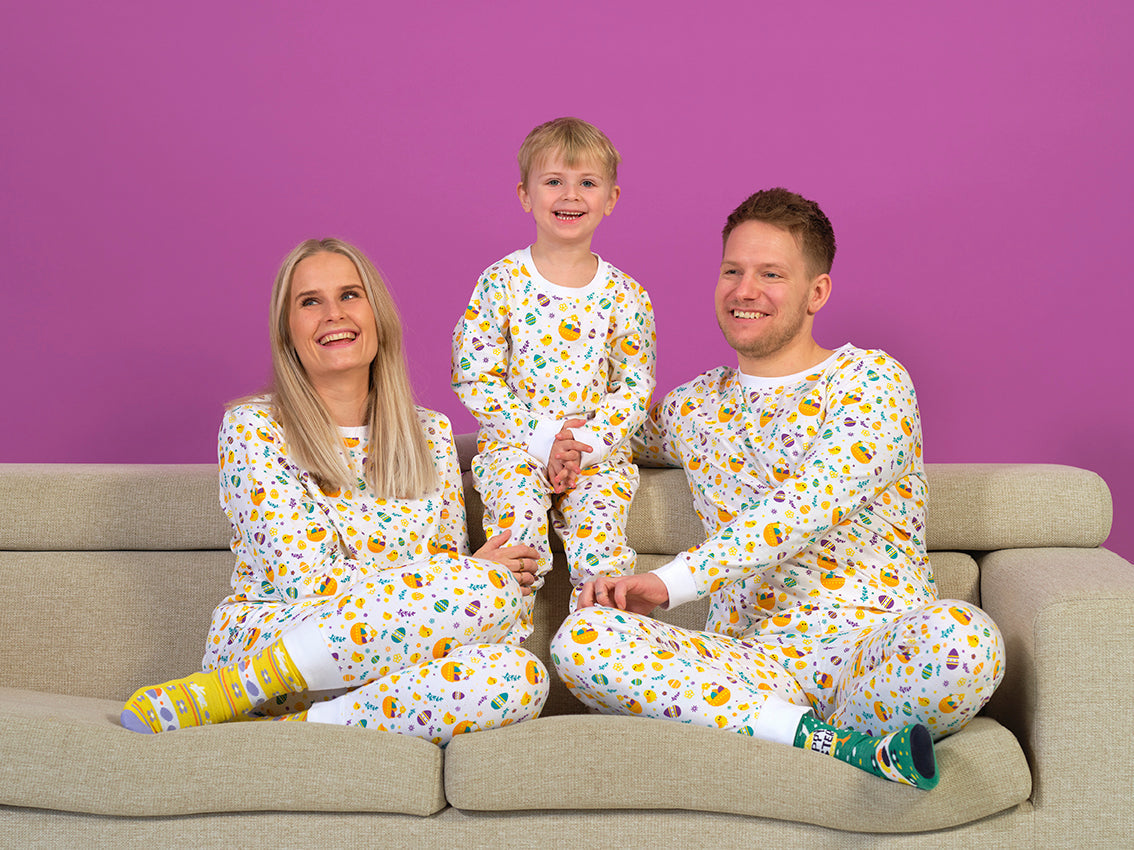 En familie i en sofa iført hvit påskepyjamas.