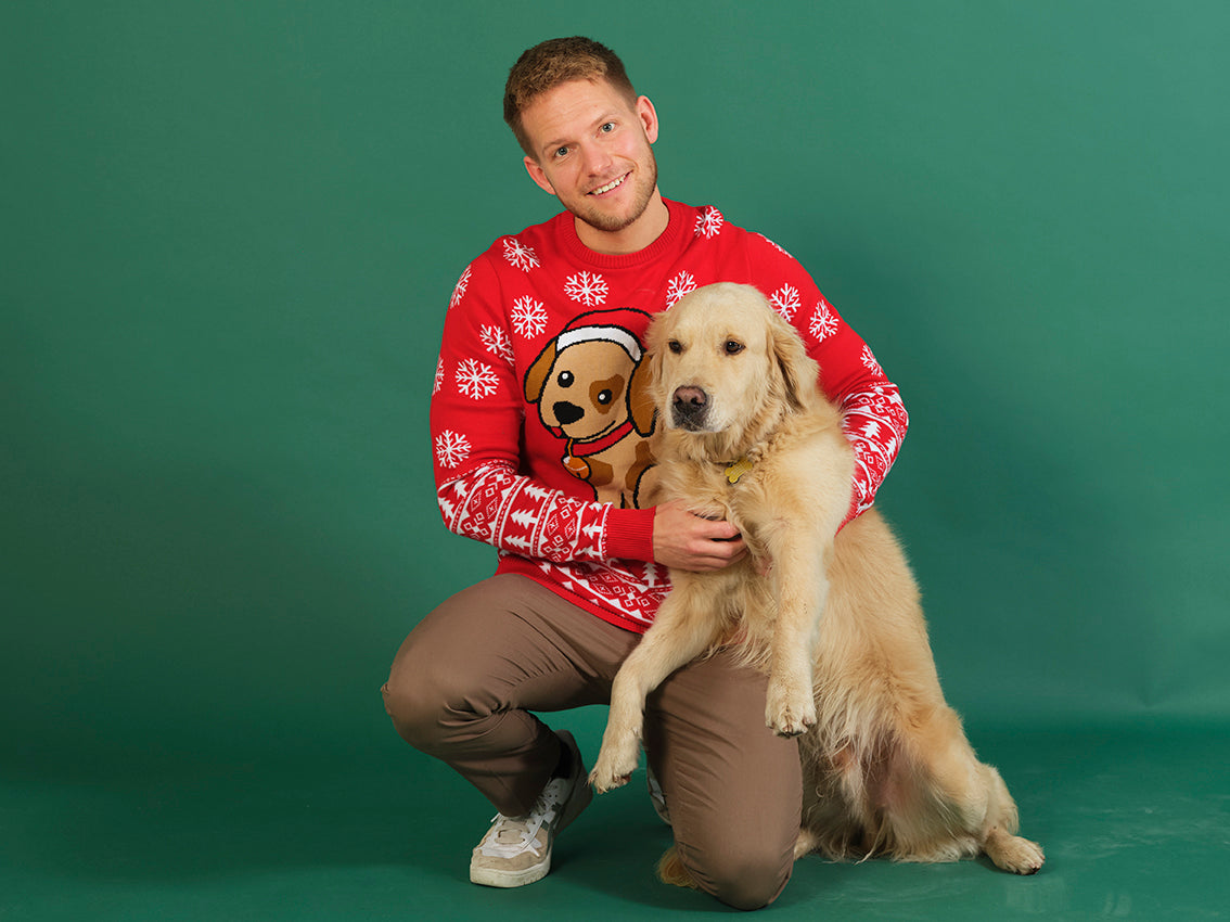 En mann med hund har på seg en rød julegenser med hund på.