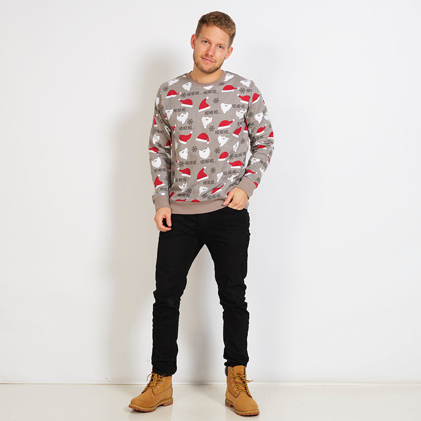 En poserende mann i grå julepyjamas med nisseluer.