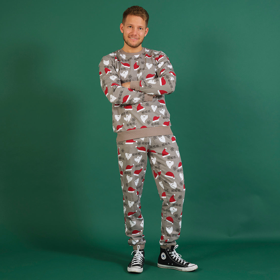 En mann i grå julepyjamas med nisseluer.