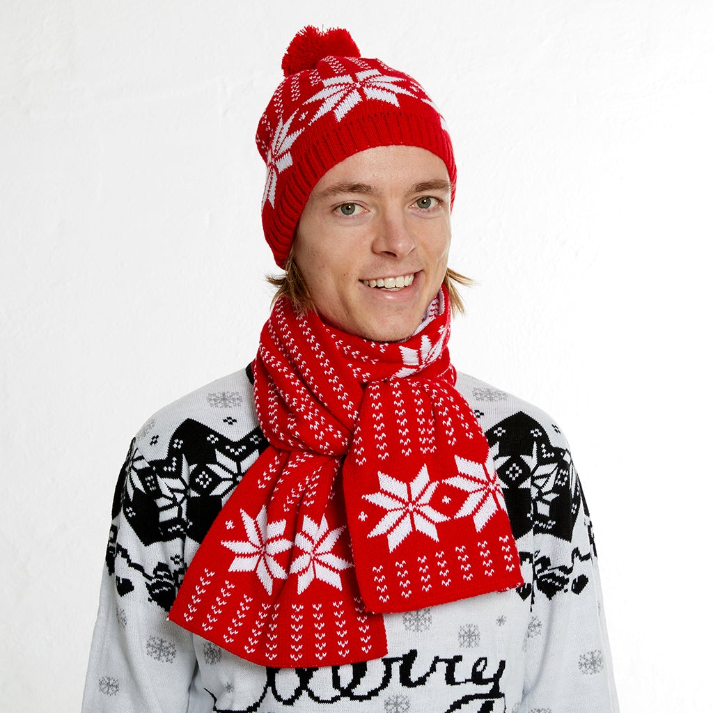 En mann med rød julelue og skjerf med snøfnugg på.