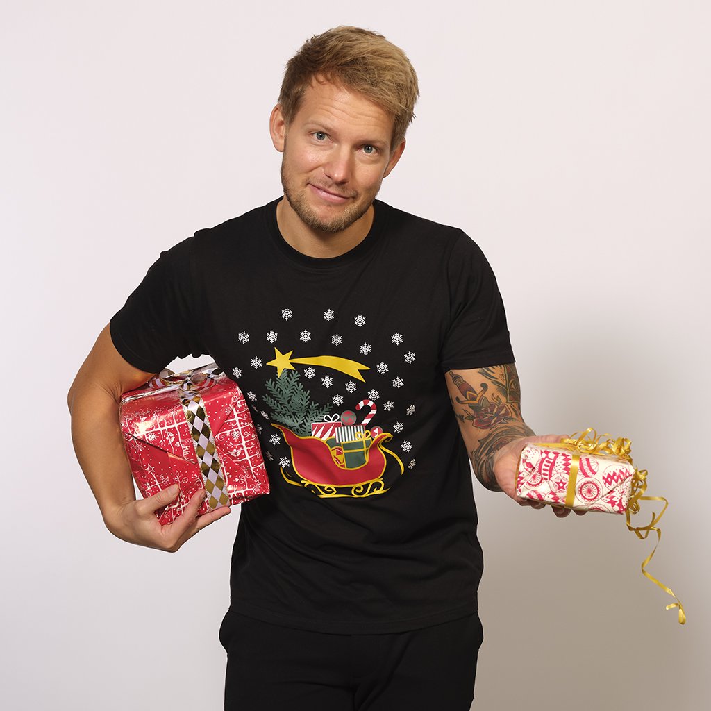En smilende mann i svart T-shirt med julenissens slede på.