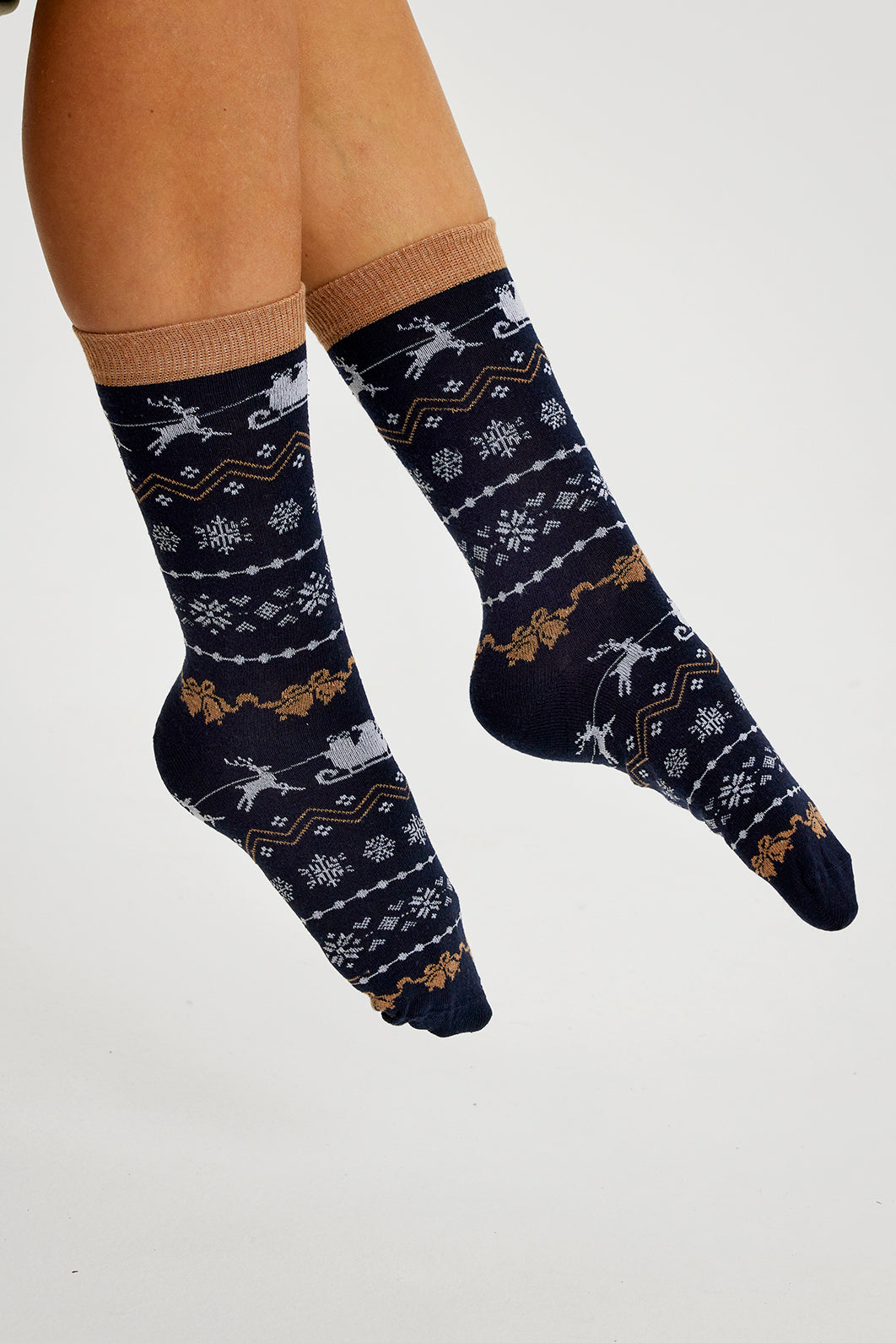 Et par føtter i svarte julesokker med julemønster på.