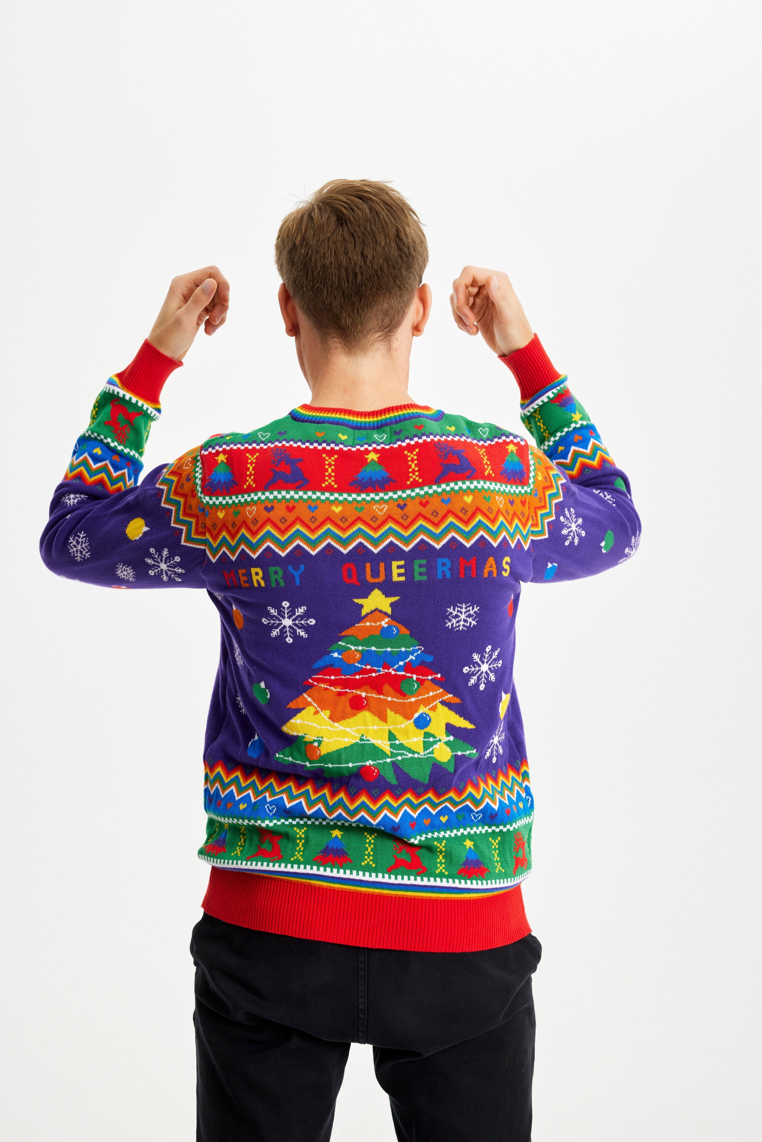 En mann står med ryggen til og har på seg en fargerik julegenser med påskriften 