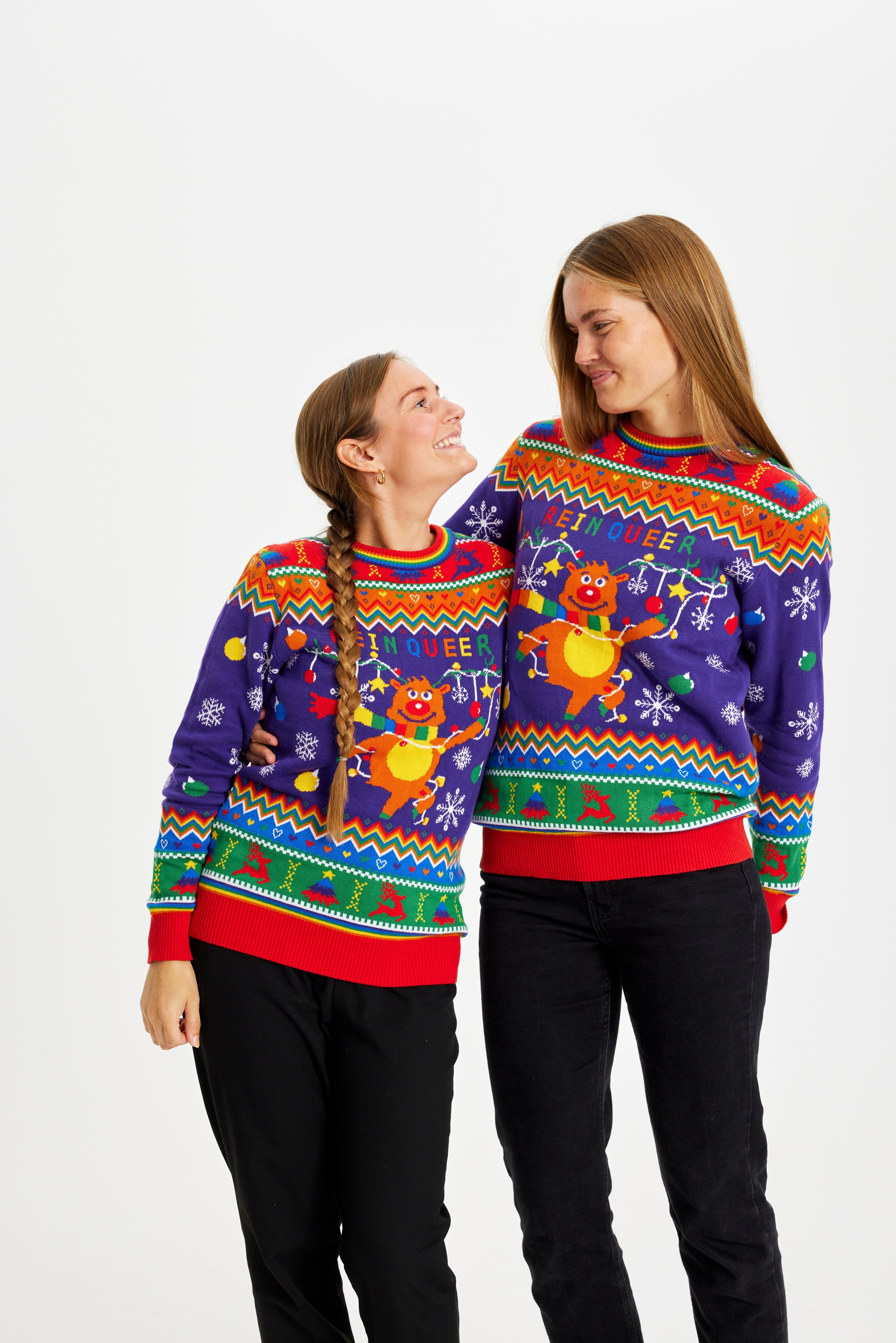 To kvinner iført en fargerik julegenser med påskriften 