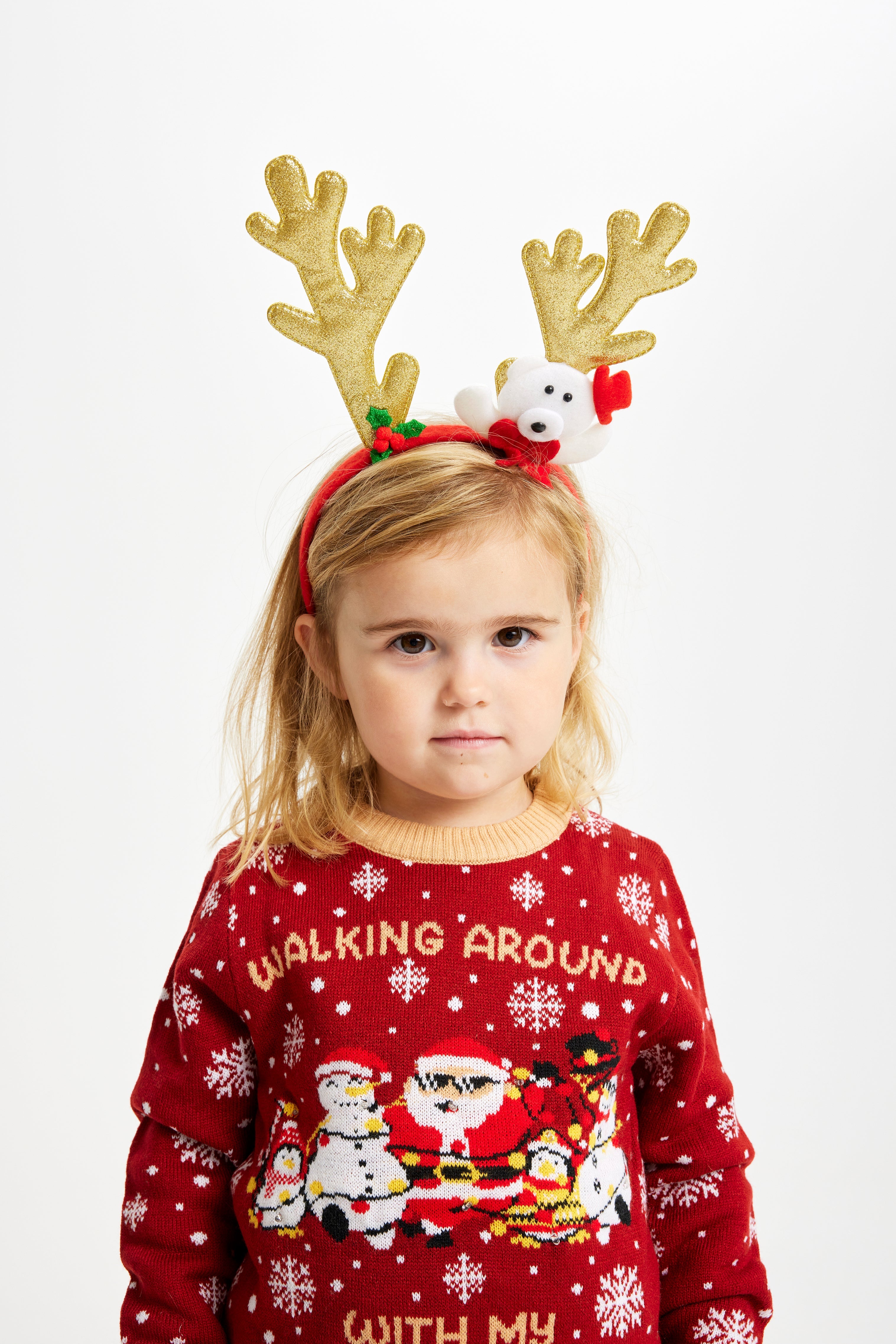 Et barn med reinsdyrgevir og en rød julegenser med sitatet 