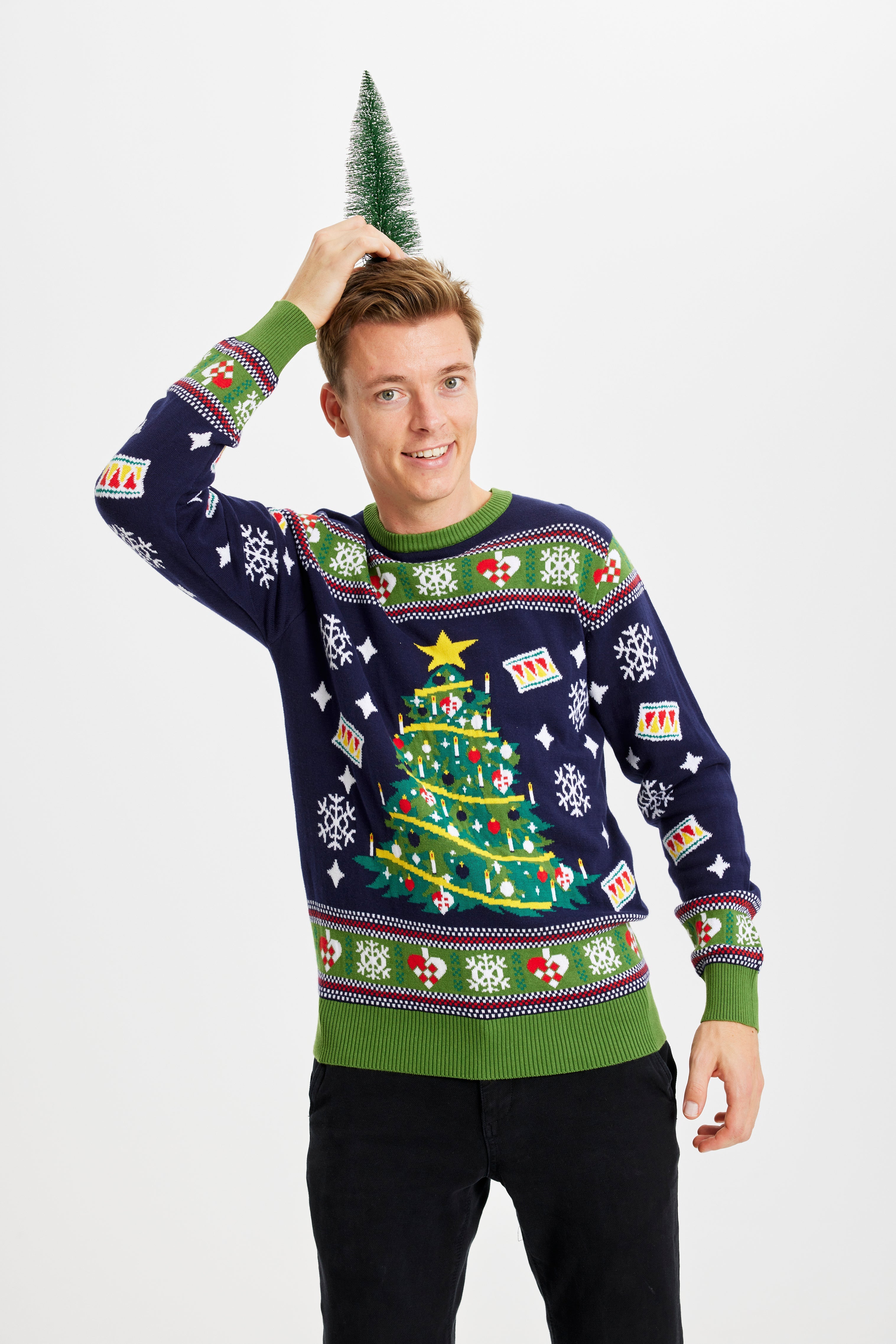 En mann med julepynt på hodet har på seg en julegenser med juletre og lys.