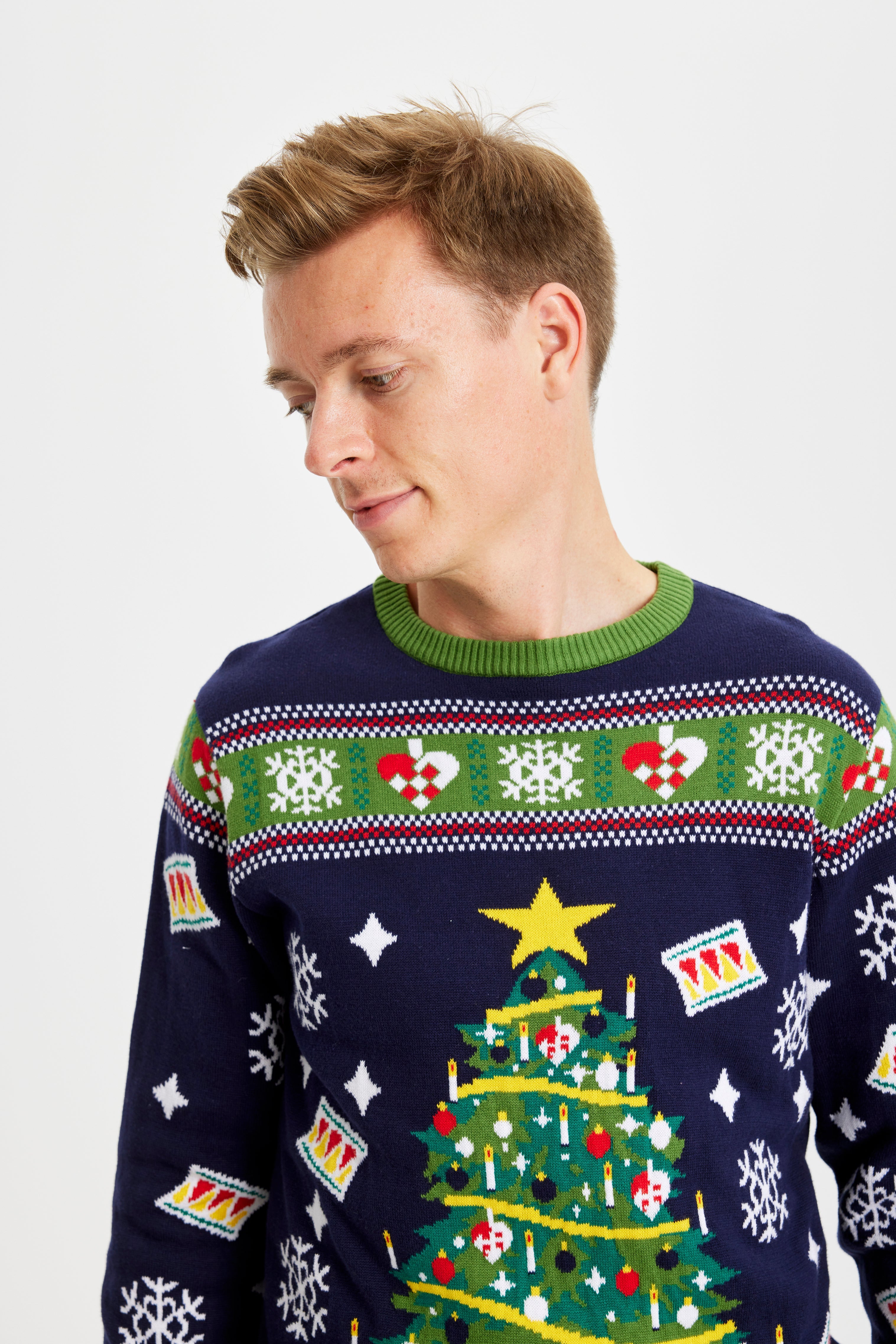 En mann ser til siden og har på seg en julegenser med juletre og lys.