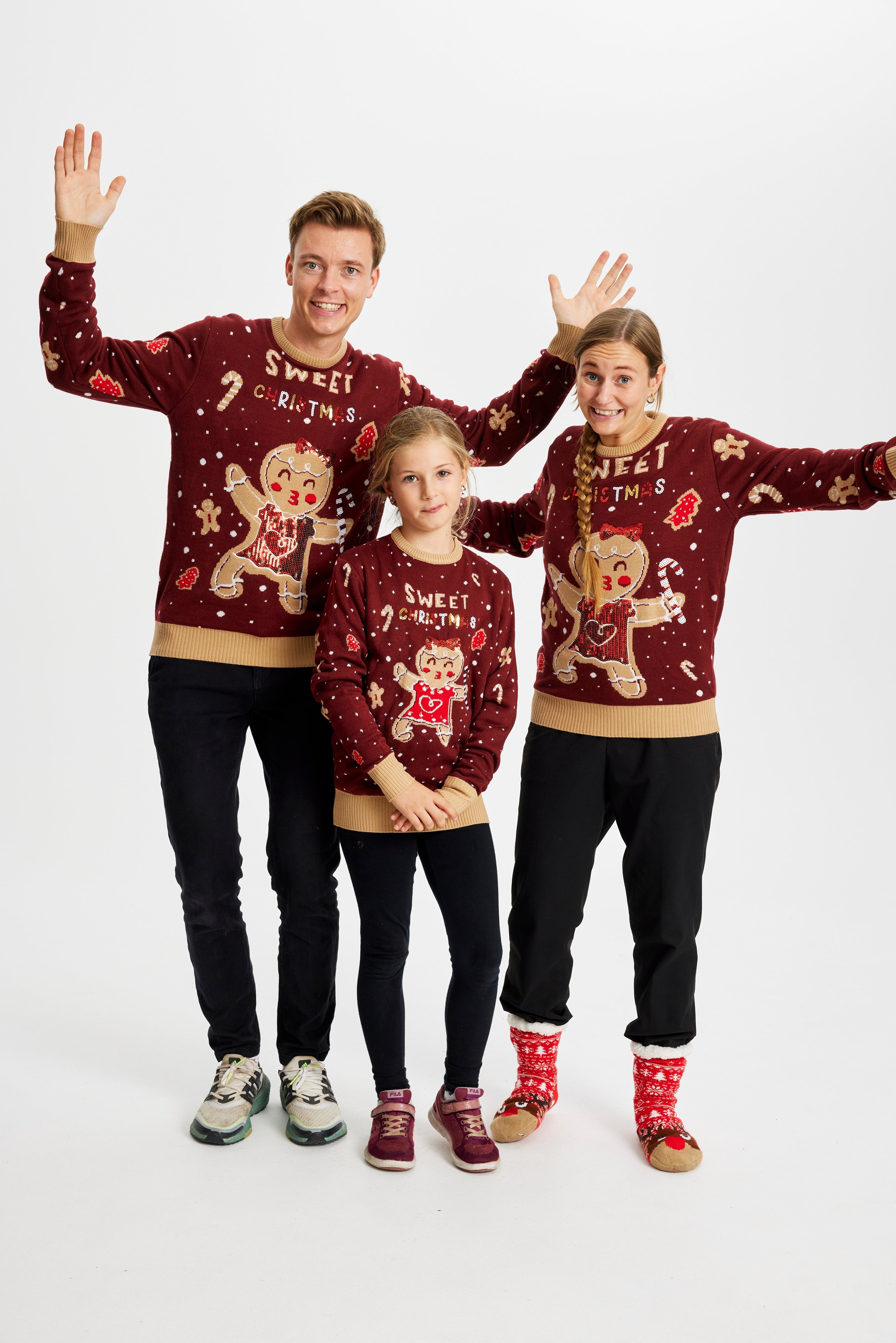 En familie har på seg en rød julegenser med lys og en småkake.