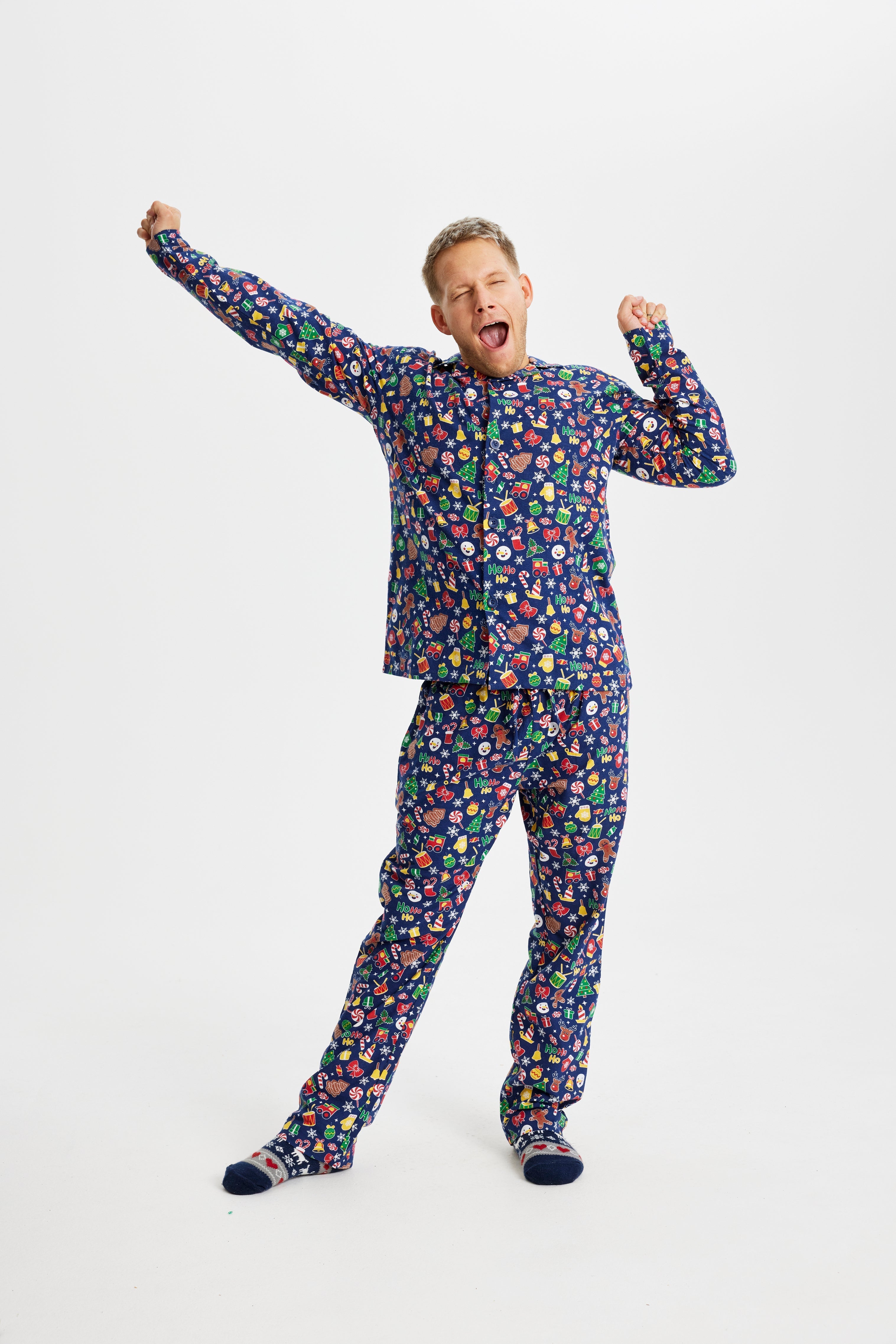 En gjespende mann i blå julepyjamas.