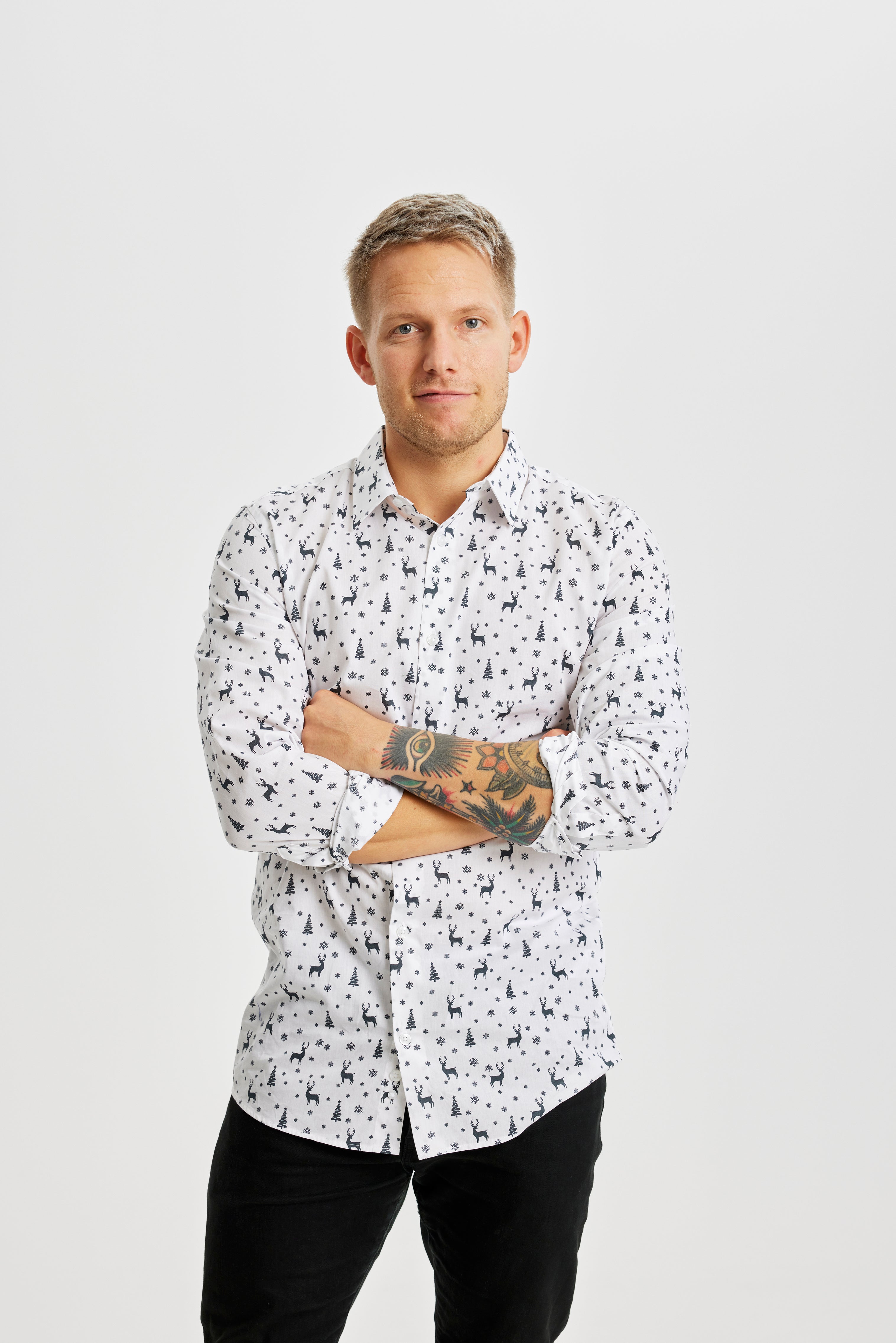 En mann med armene i kors har på seg en hvit juletrøye.