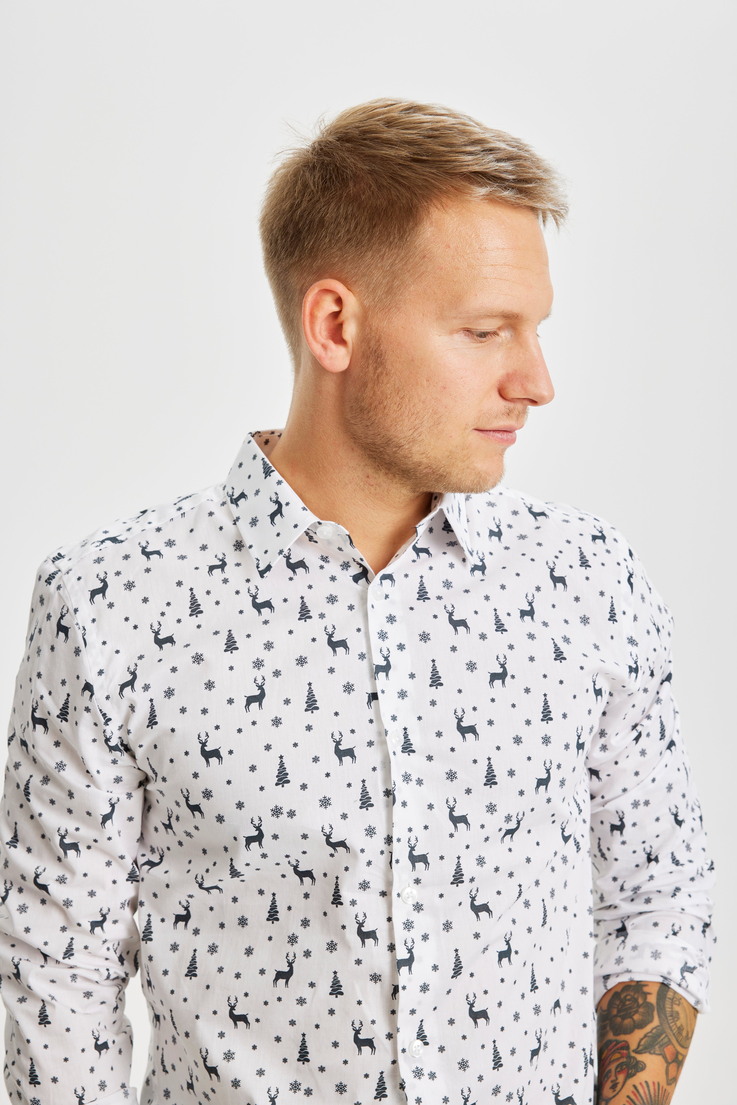 En mann ser til siden og har på seg en hvit juletrøye.