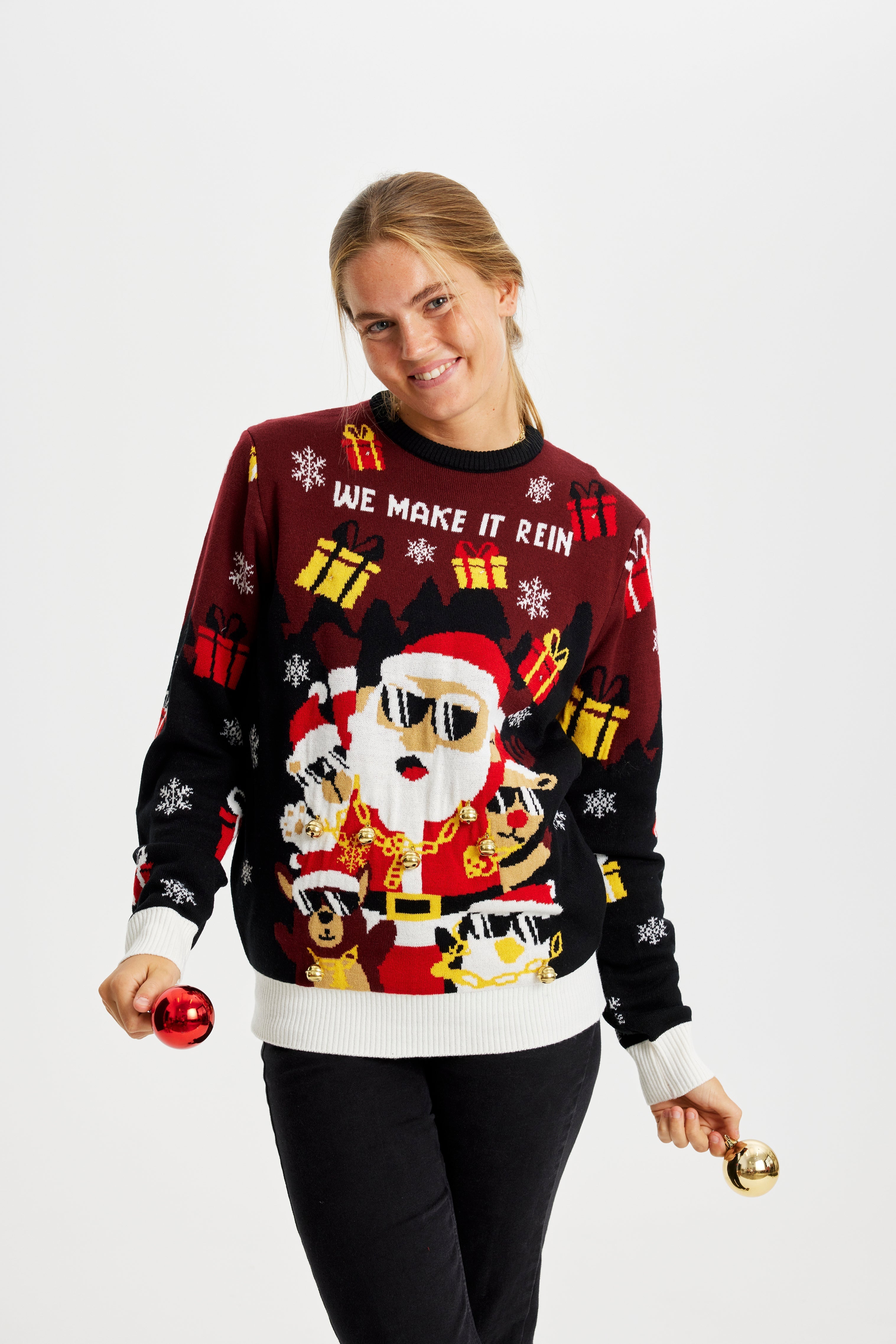 En smilende kvinne iført en selvlysende julegenser med gaver.