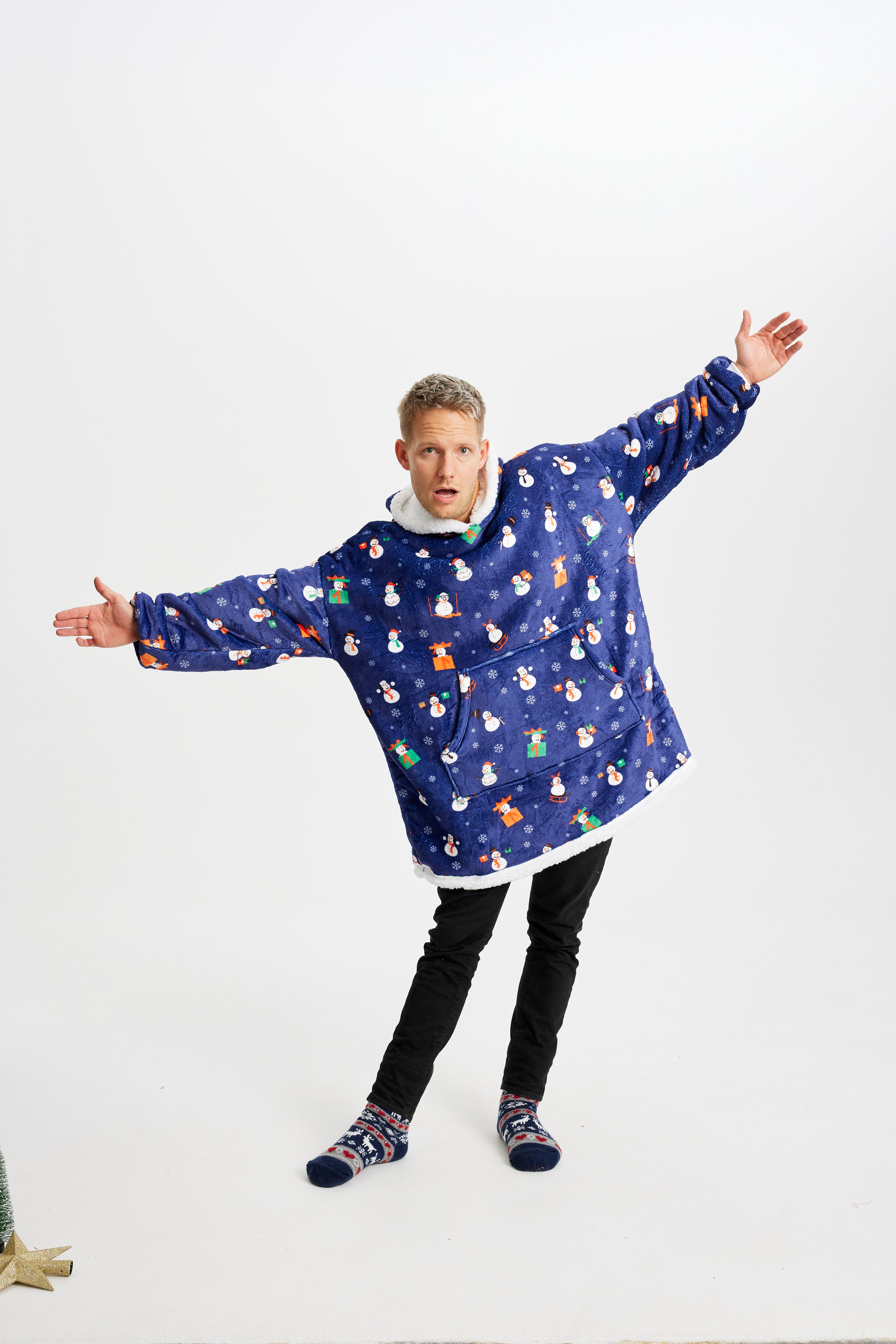 En poserende mann i blå julegenser med snømenn.