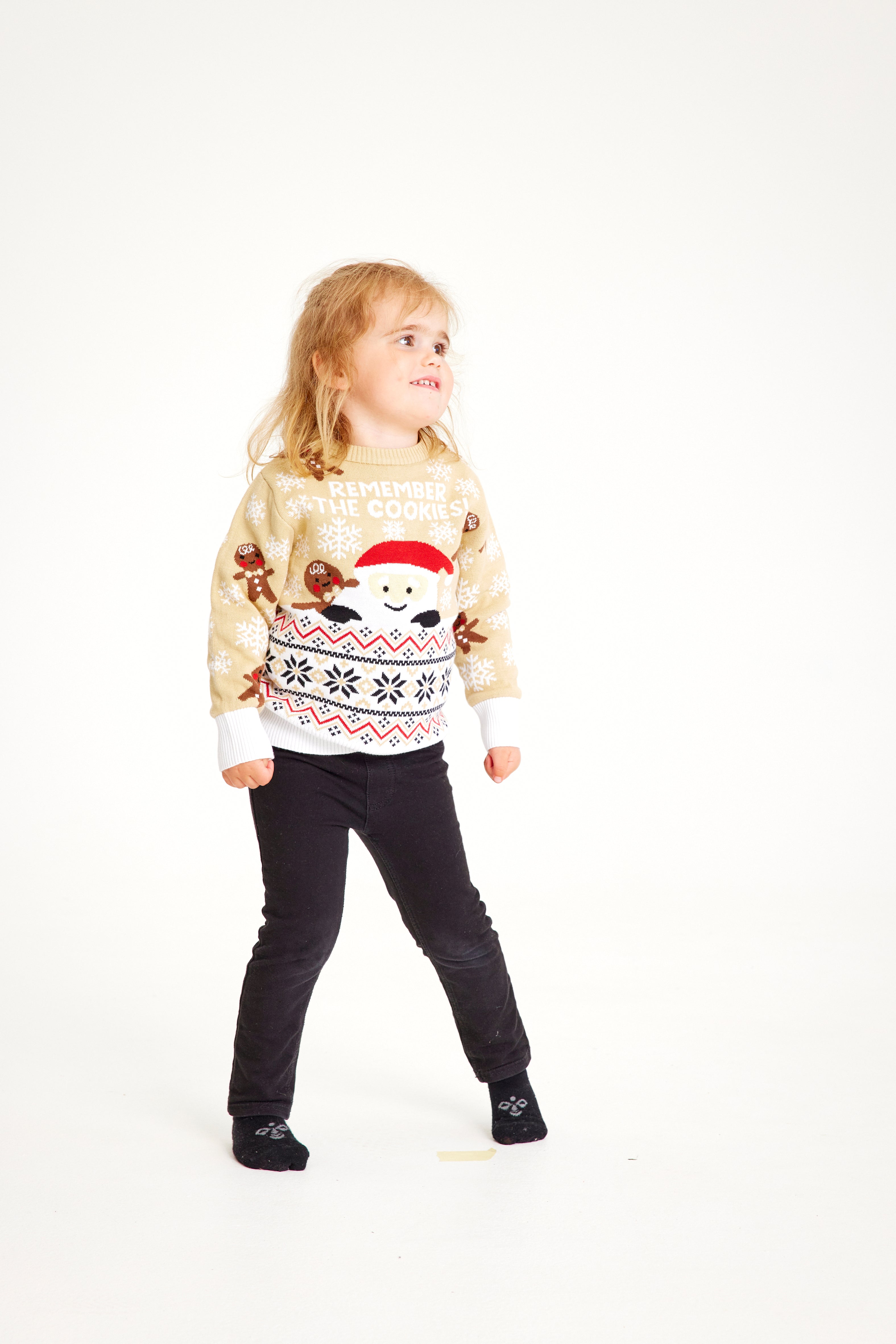 Et barn iført en beige julegenser med kjeks.