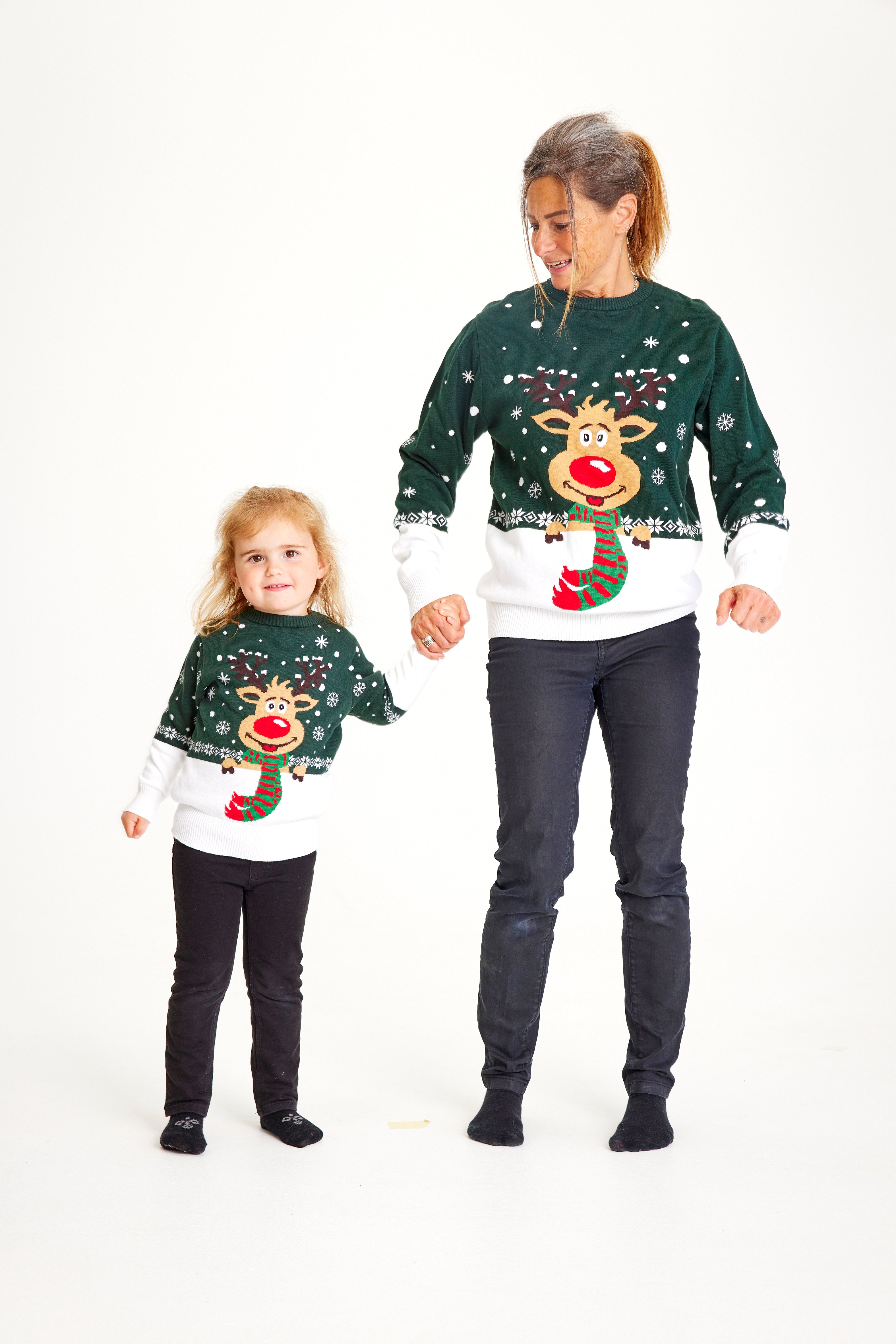 Et barn og en kvinne med grønn julegenser med reinsdyr og snøfnugg.