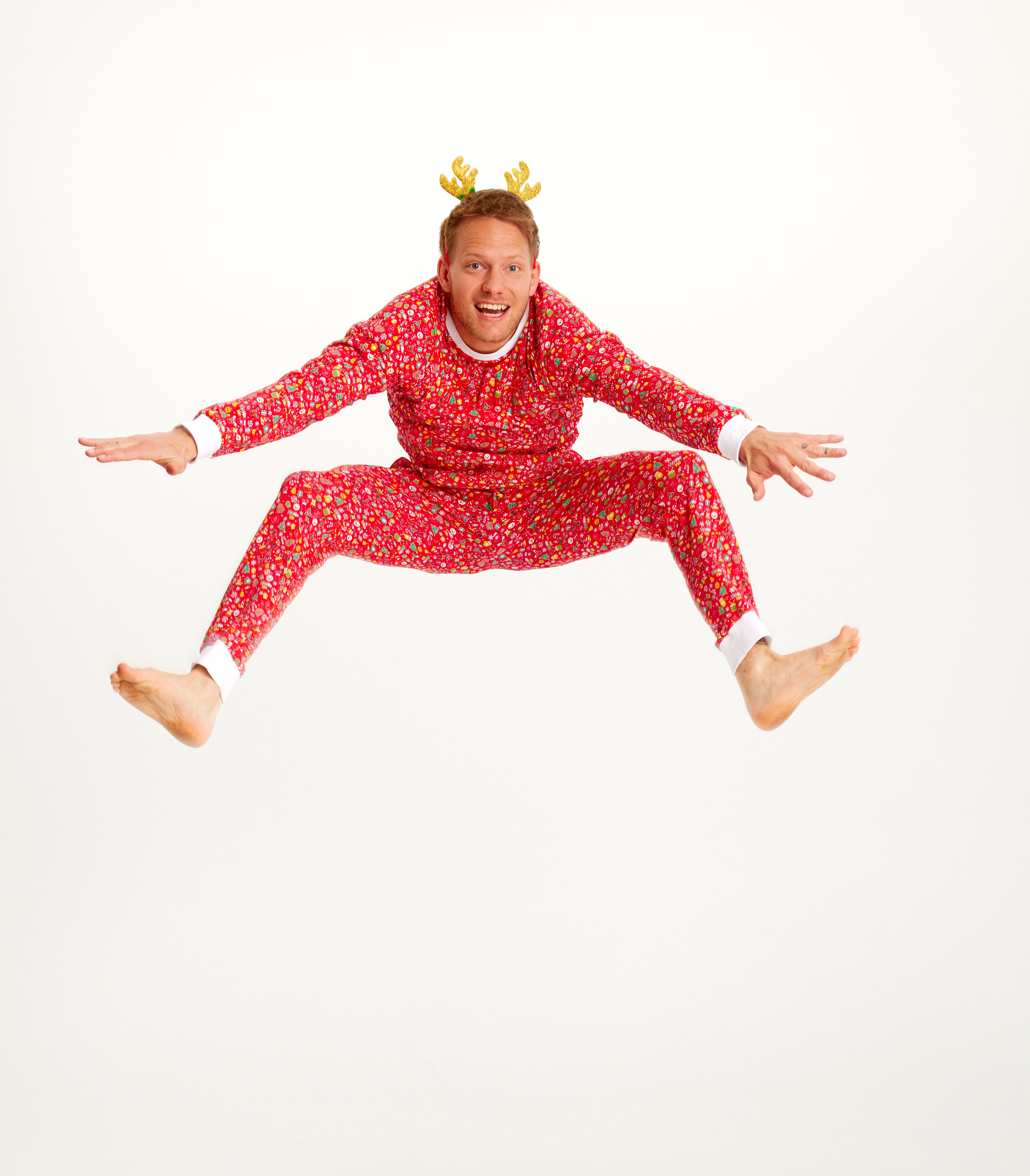 En hoppende mann i rød julepyjamas.