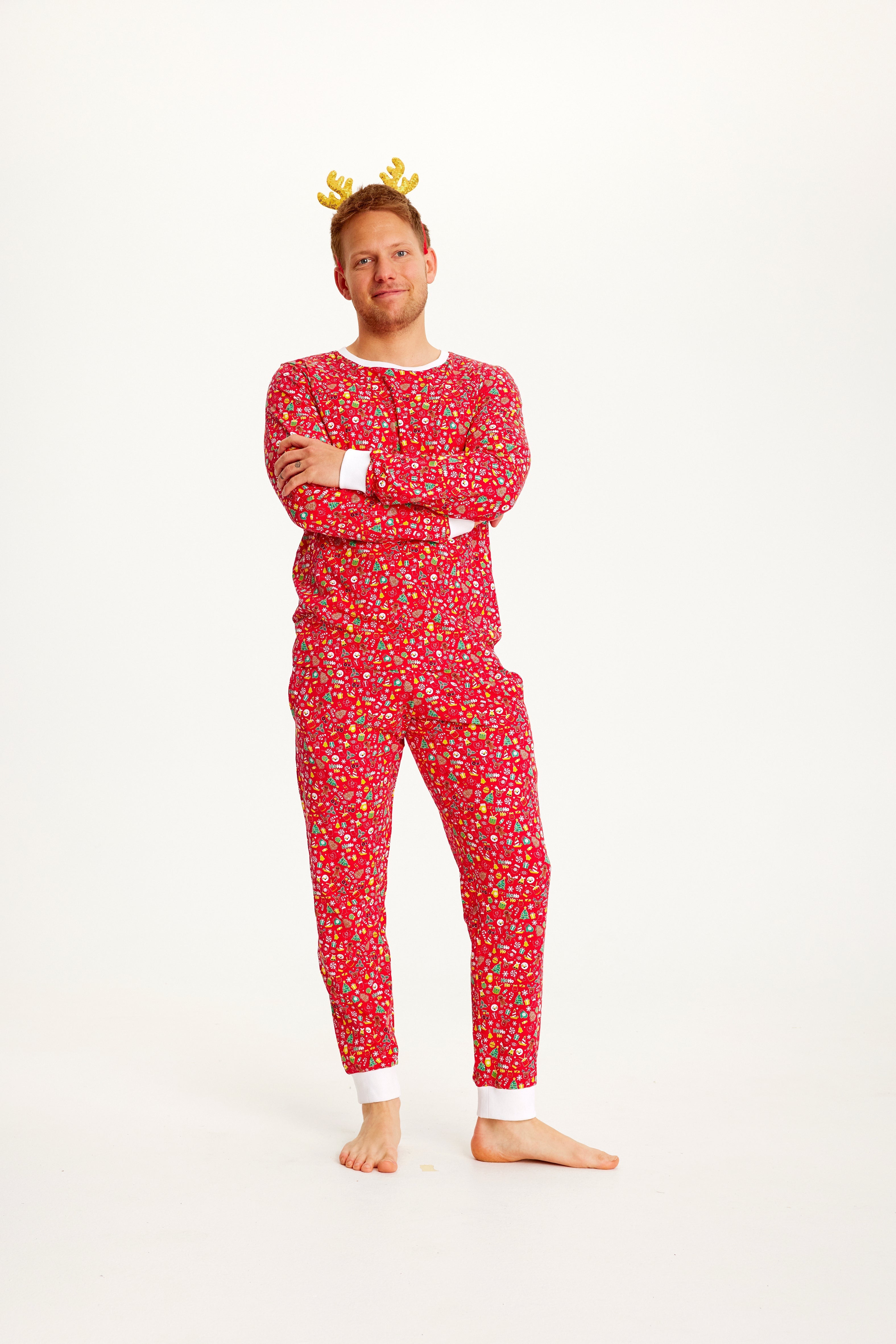 En mann med hendene i kors iført rød julepyjamas.