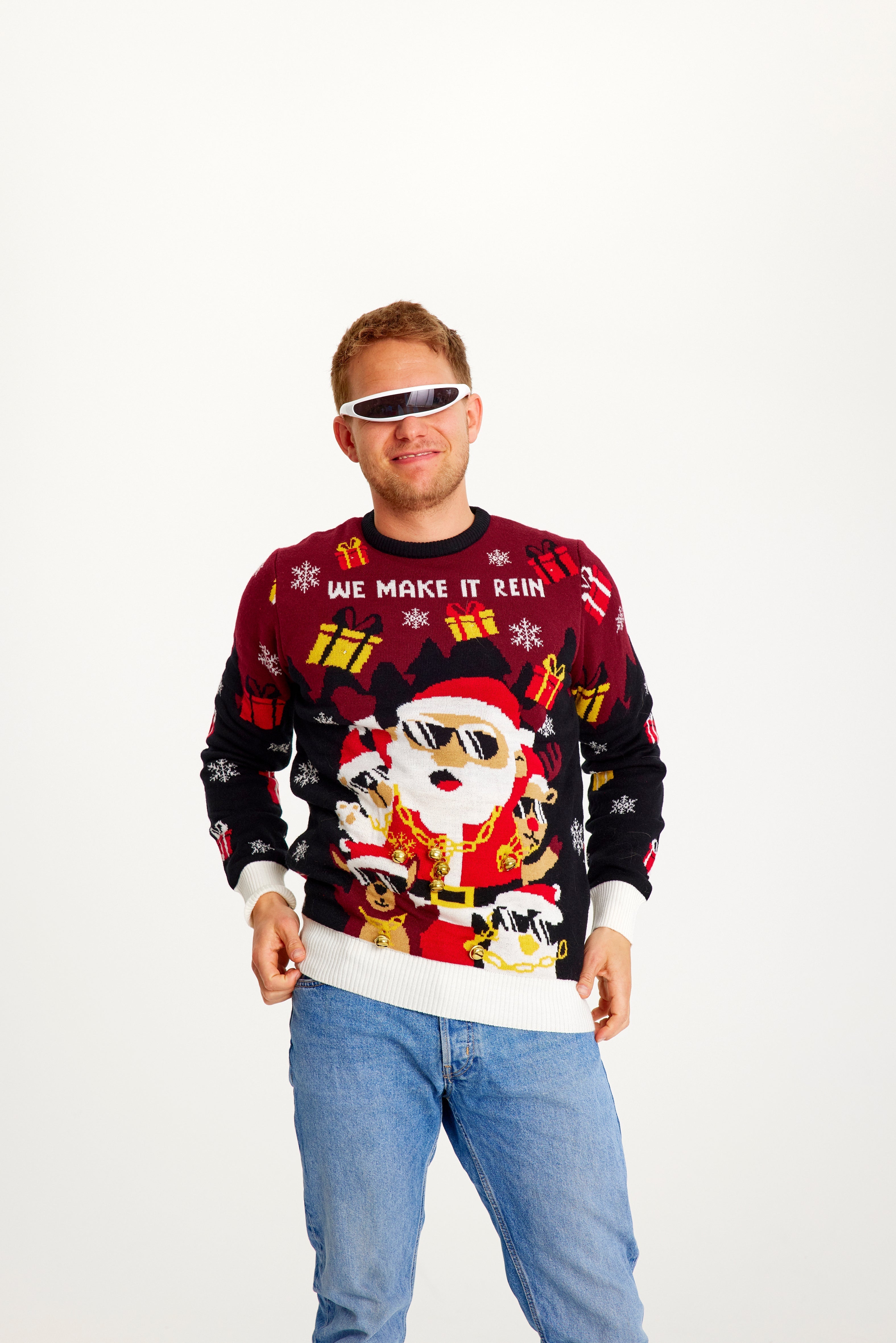 En mann med solbriller poserer iført en selvlysende julegenser med gaver.
