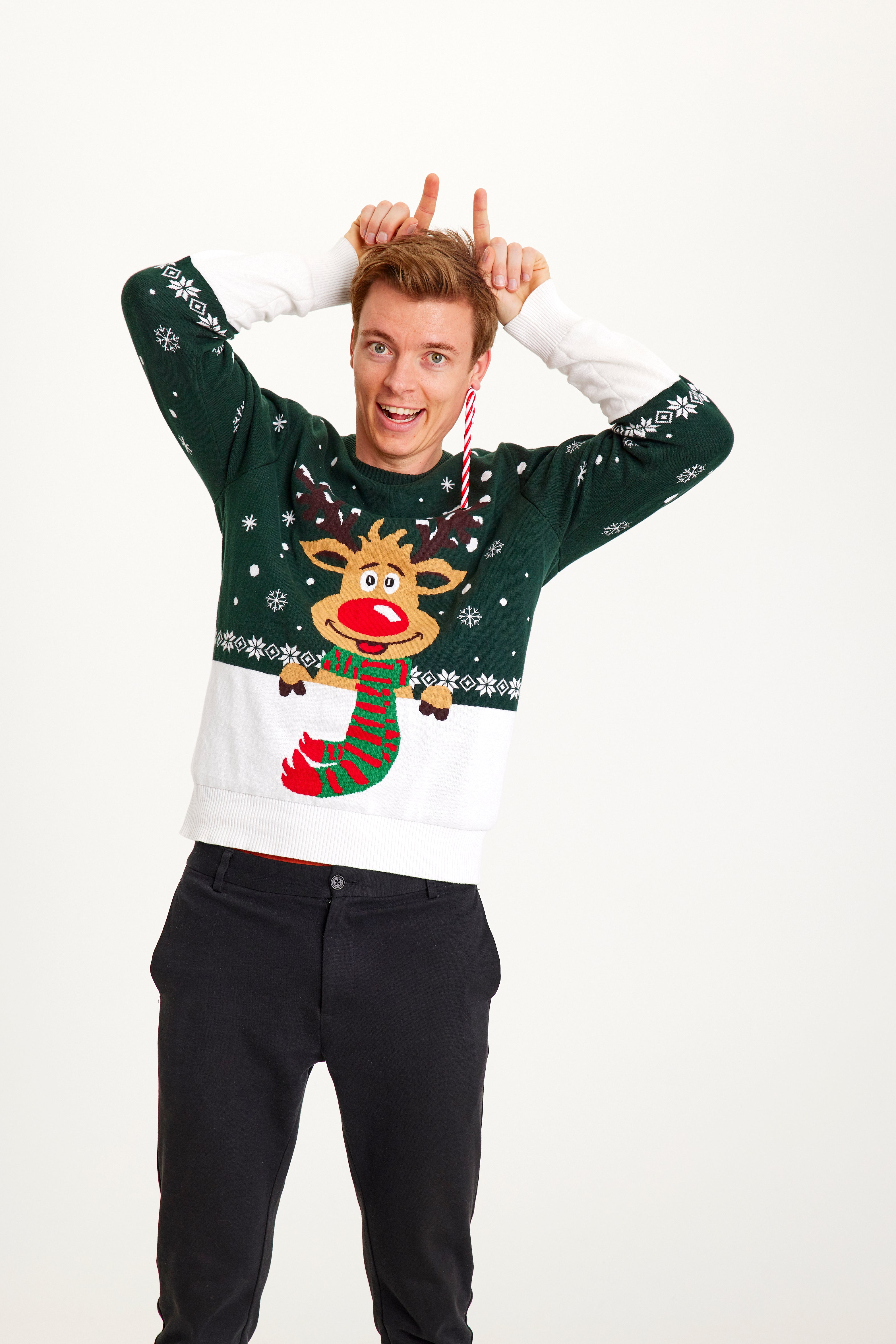 En mann iført en grøn julesweater med rensdyr og snefnug på.