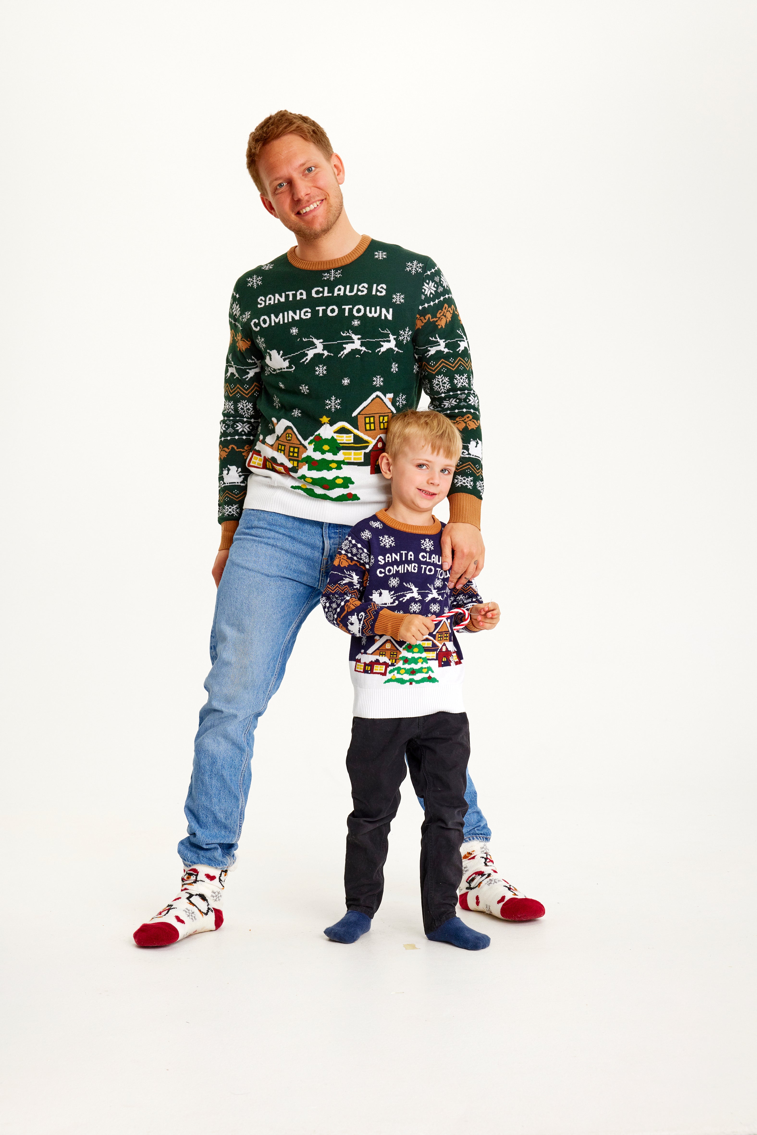 Et barn og en mann iført julegensere med snølandskap på.