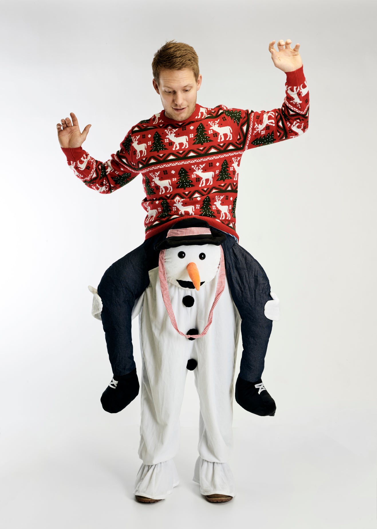 En mann i julegenser iført et carry-me-kostyme som ser ut som en snømann.