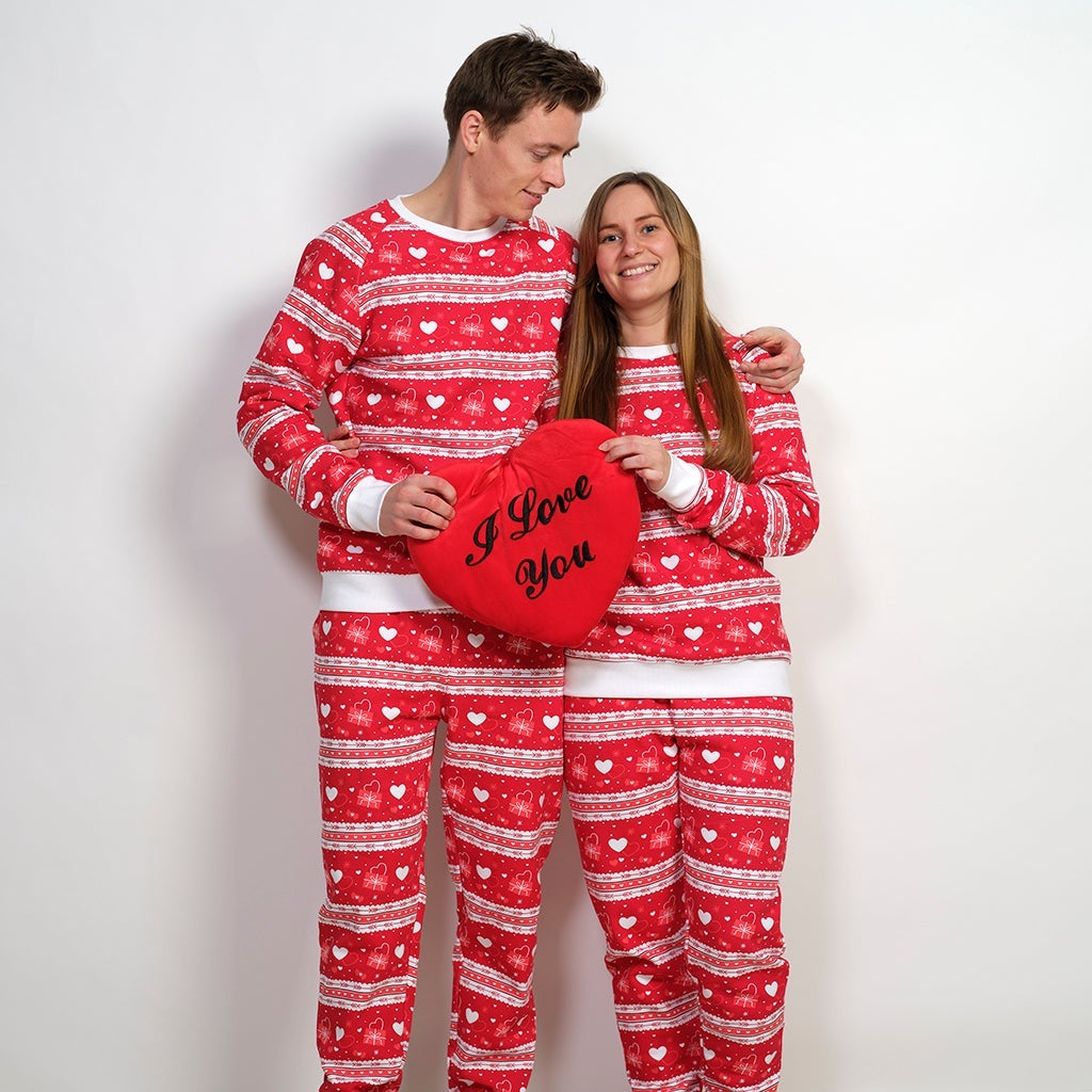 Et par poserer sammen i røde valentinssett med hvite hjerter på.